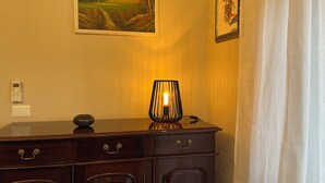 A room with a wooden cabinet, a lamp, a painting, and a thermostat on the wall. - Cozy apartment in the center of Cosenza equipped with every comfort (Cosenza)