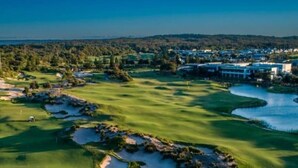 Un parcours de golf avec des bunkers, un étang et une zone résidentielle en arrière-plan.