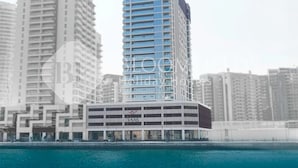 Un immeuble moderne de grande hauteur, doté d’une façade bleue remarquable, et entouré d’autres immeubles de grande hauteur.