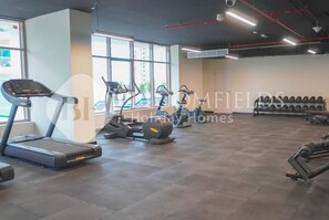 A gym with treadmills, elliptical machines, and weight benches. - Bloomfields Canal View 2Br Business Bay (Dubai)