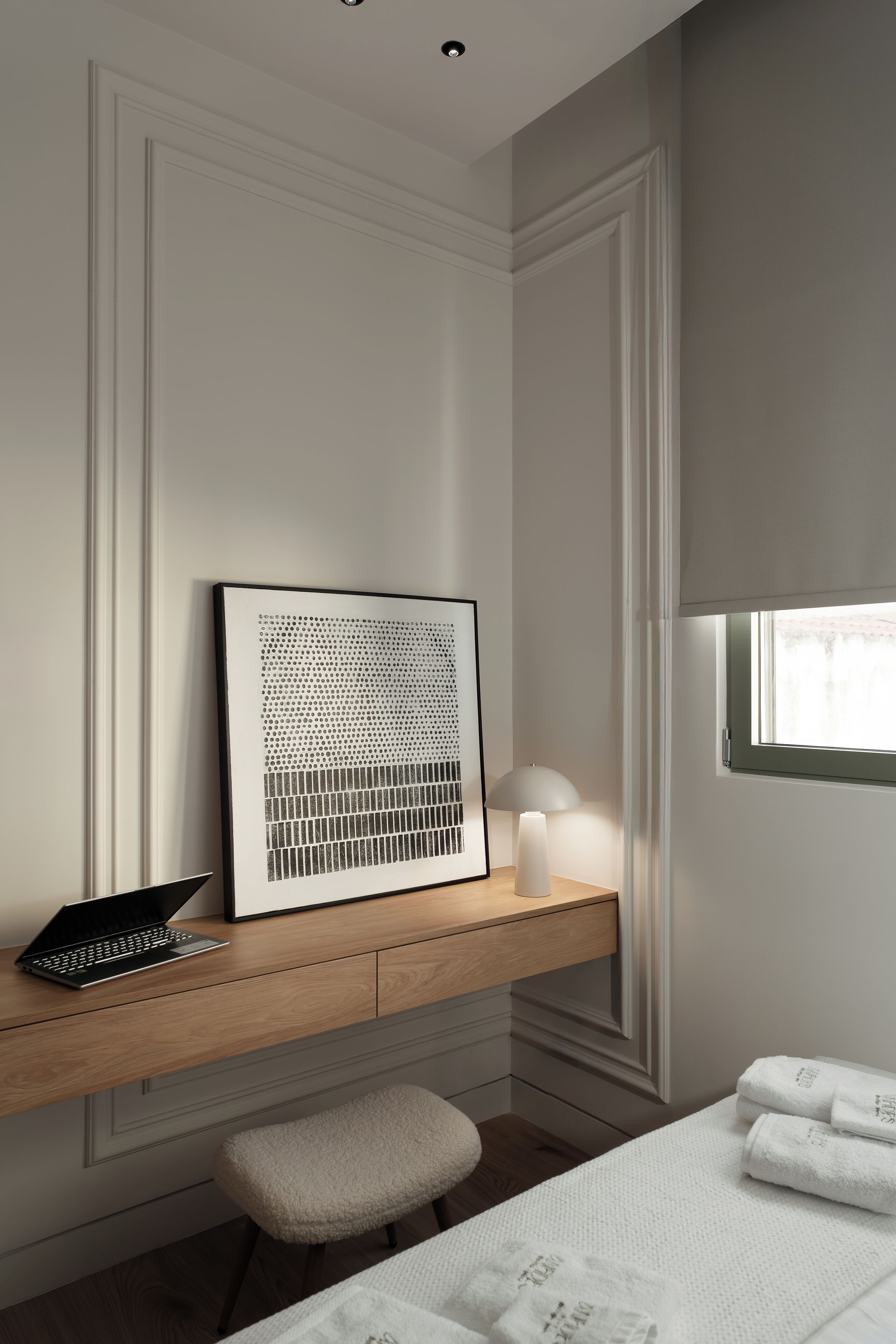 Een moderne slaapkamer met een houten bureau, een lijstwerk, een lamp en een raam met uitzicht.
