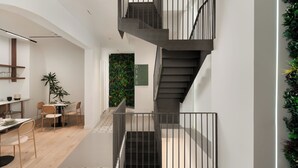 A modern interior with a staircase, dining area, and a wall with greenery. - Anfides Boutique Hotel (Patras)
