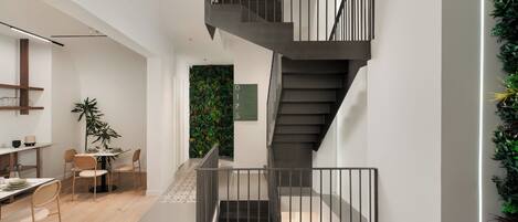 Um interior moderno com escada, área de jantar e parede com vegetação.