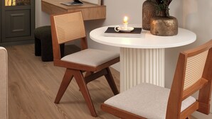 A modern dining area with a round table, two wooden chairs, a vase with flowers, and a laptop on the table. - Anfides Boutique Hotel (Patras)