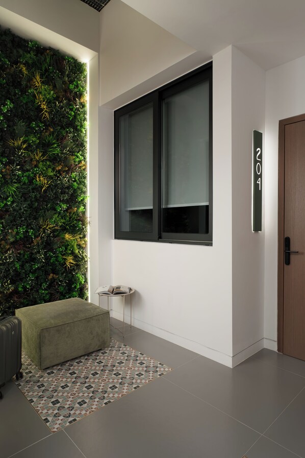 A modern interior with a green living area, a large window, and a wall-mounted number sign. - Anfides Boutique Hotel (Patras)