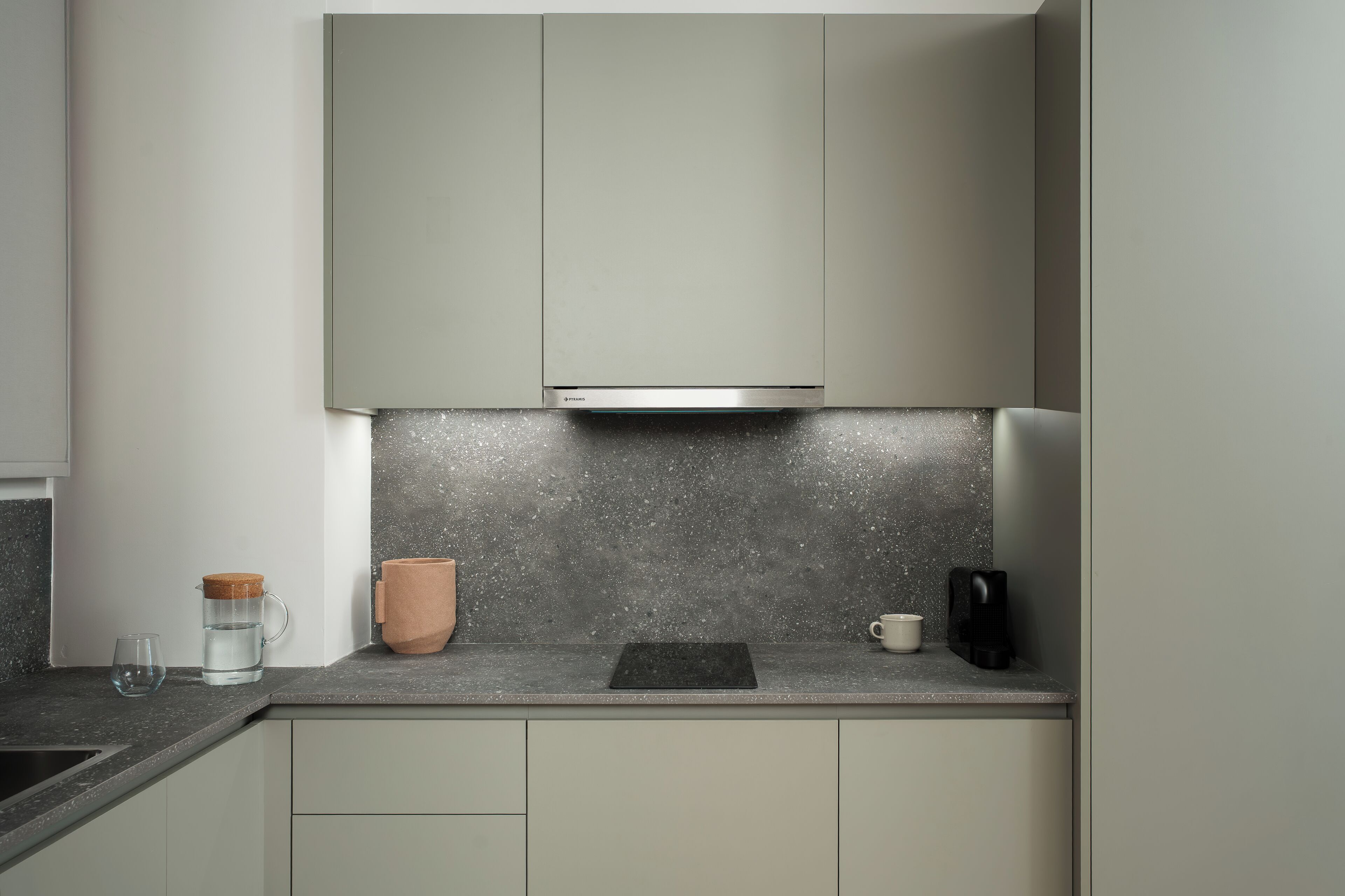 A modern kitchen with a granite countertop, a coffee maker, and a kettle.
