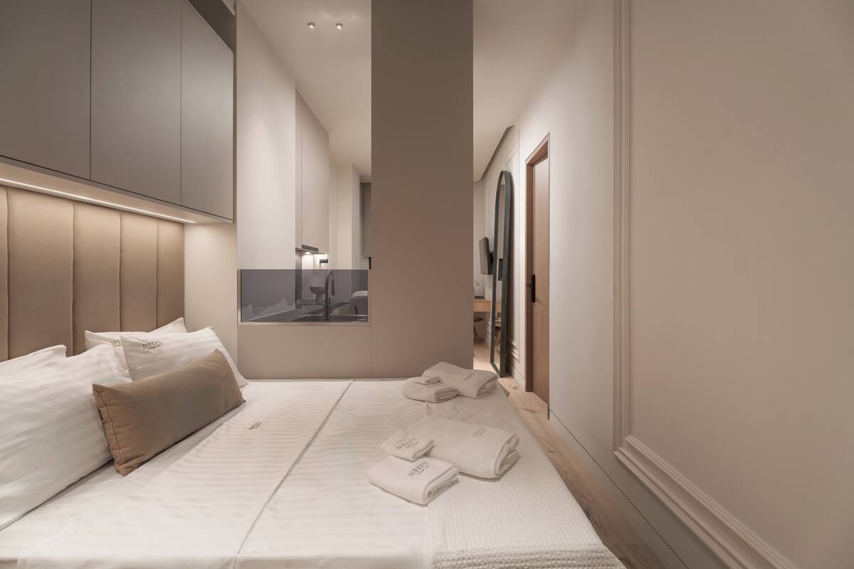 A modern bedroom with a large bed, a headboard, and a view of a bathroom.