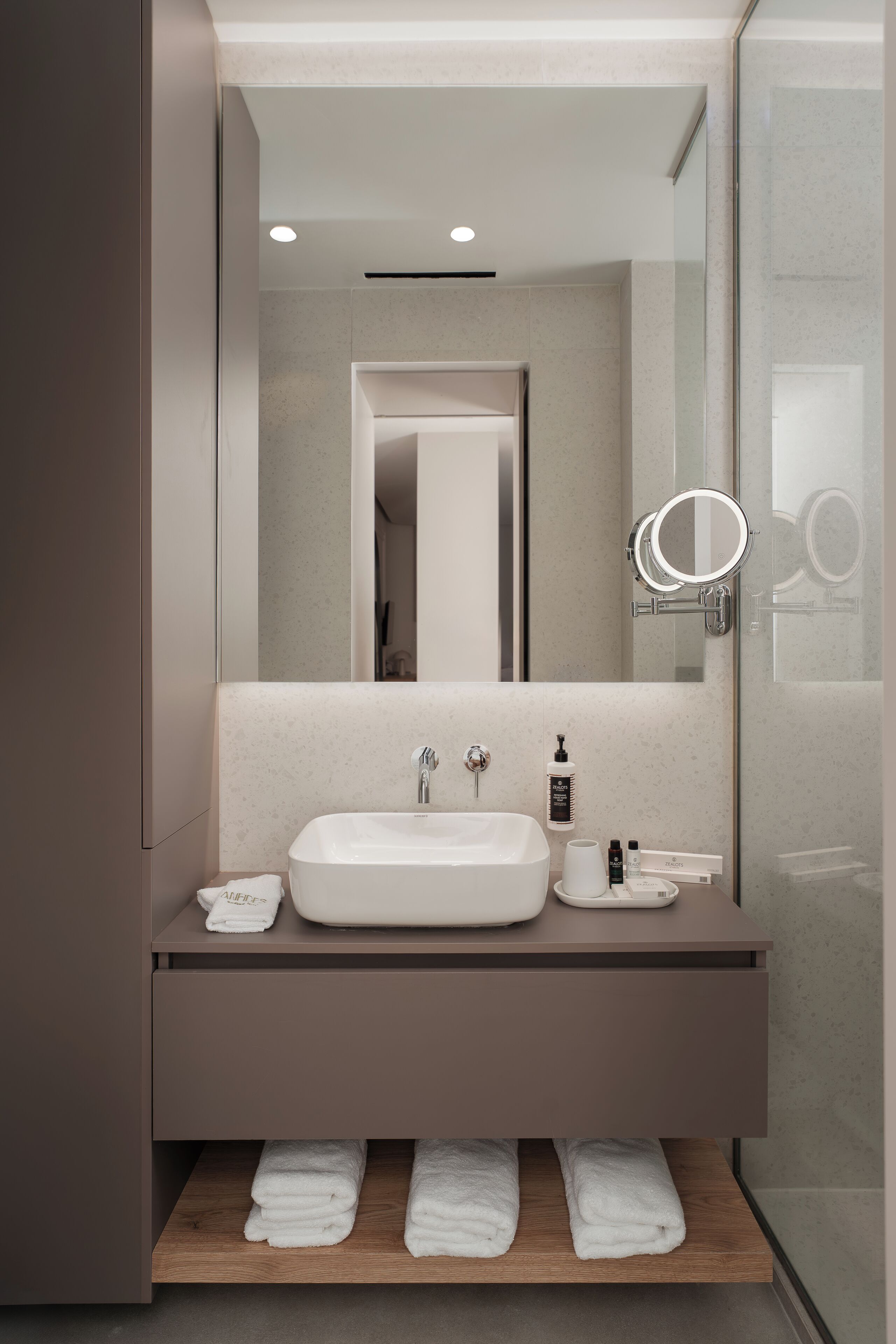 A modern bathroom with a large mirror, a white sink, and a towel rack.