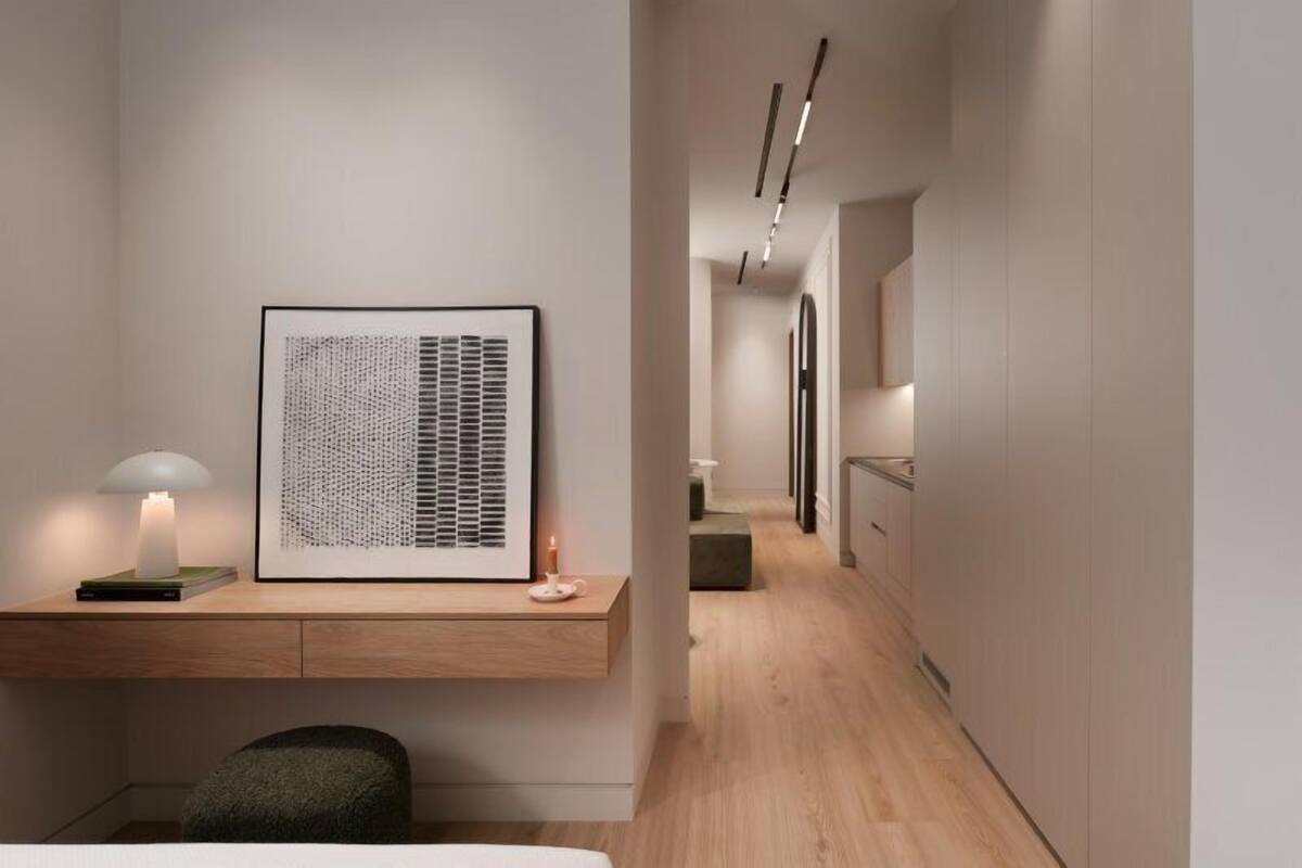 A modern interior with a desk, a framed artwork, a lamp, and a minimalist design.