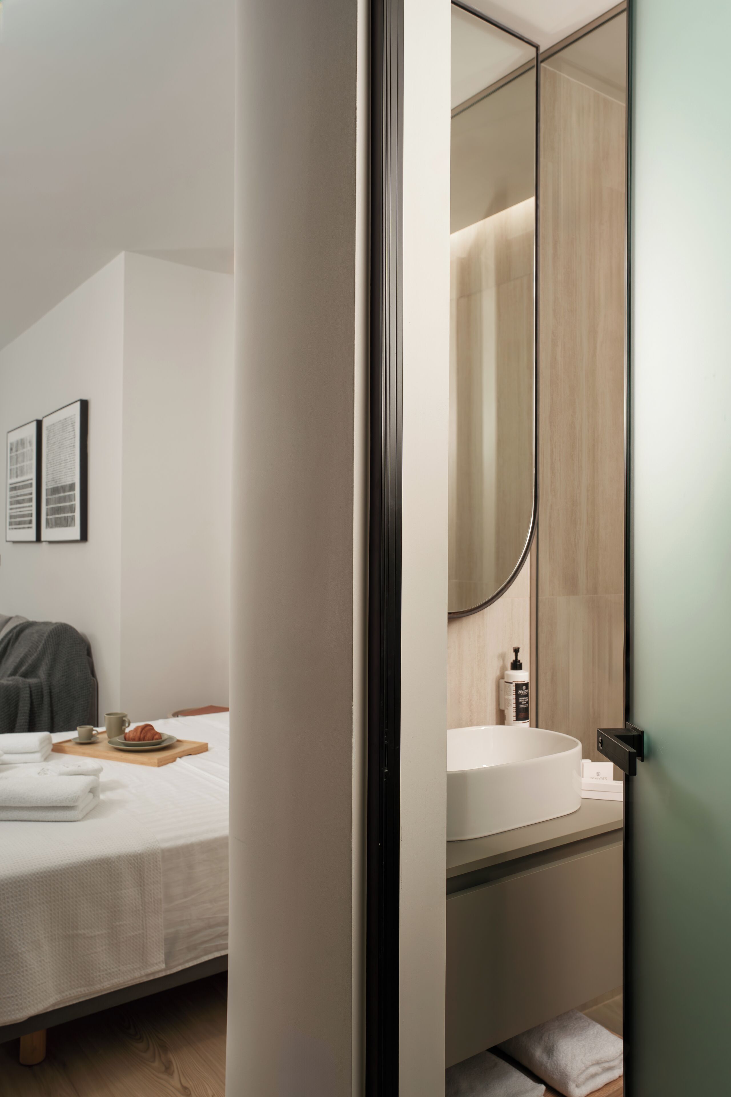 A modern bathroom with a large mirror, a white sink, and a wooden vanity.