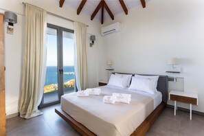 Quarto com uma cama grande, mesa de cabeceira, luminária e aparelho de ar condicionado.