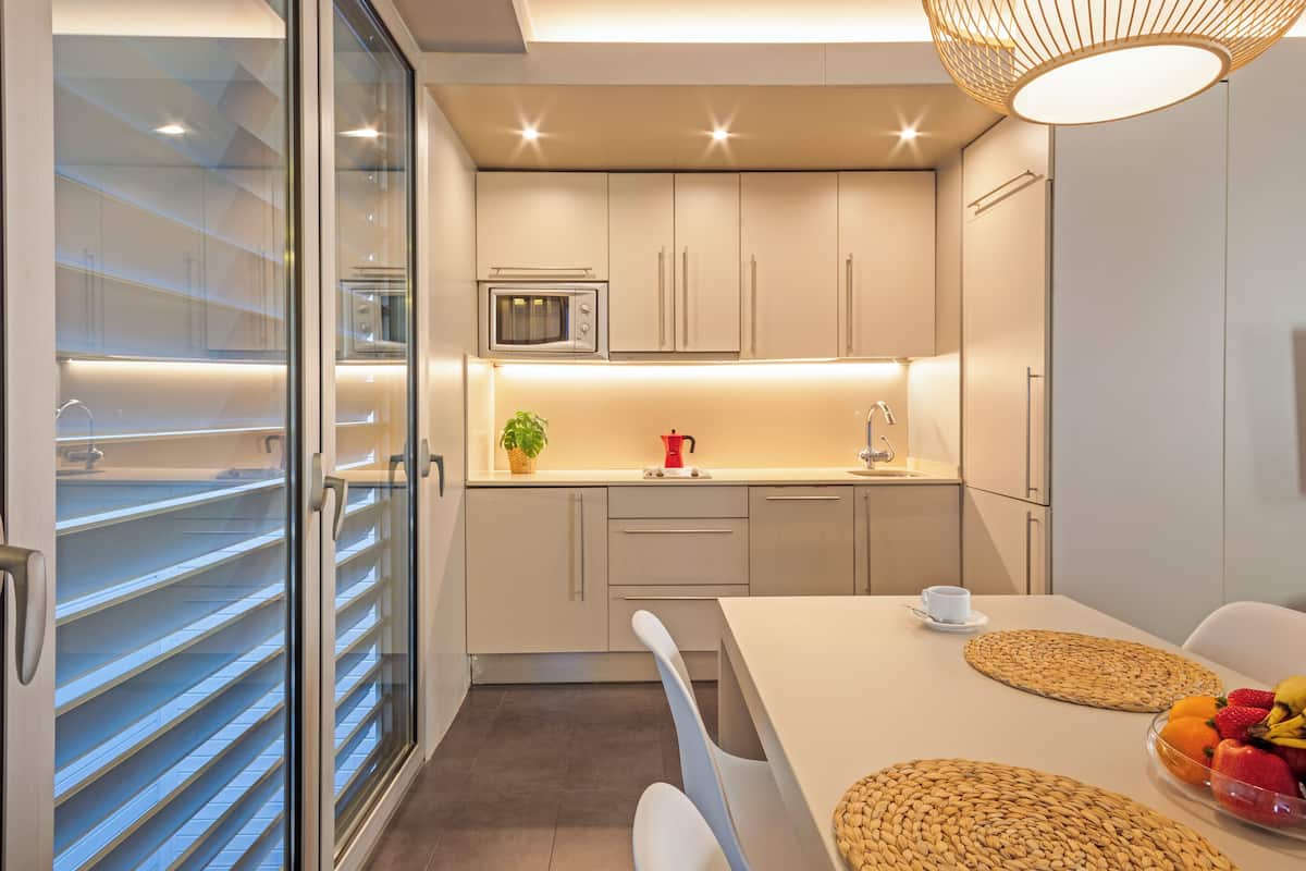 A modern kitchen with a microwave, a coffee maker, and a fruit bowl on the counter.
