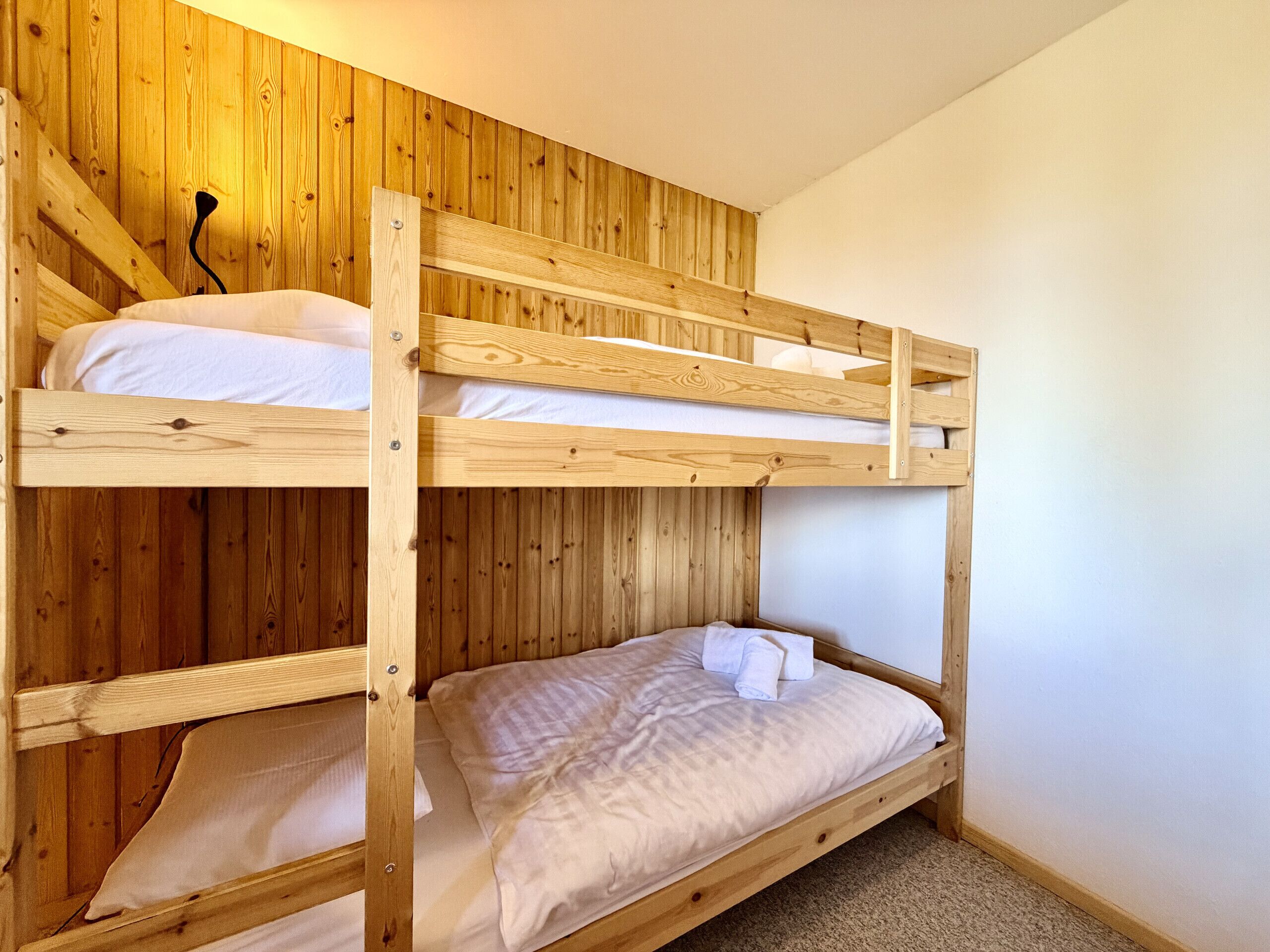 A bunk bed with wooden walls and a carpeted floor.