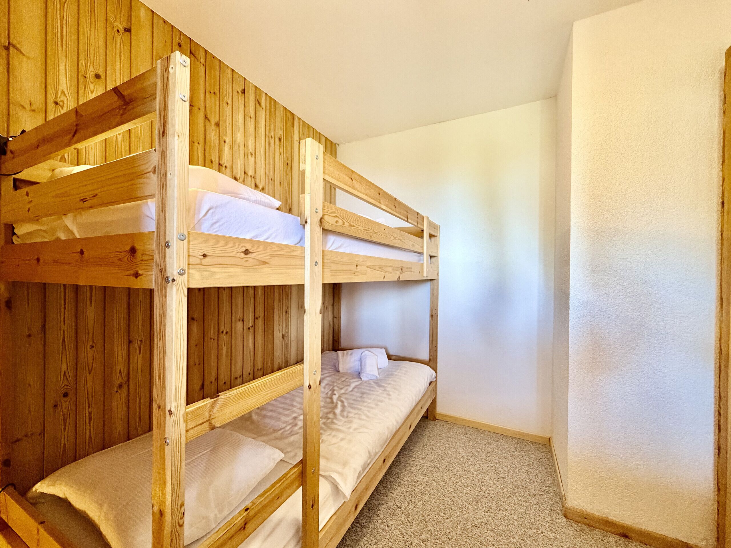 A bunk bed room with wooden walls and a carpeted floor.