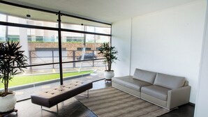 Un salon moderne avec un canapé, un banc et deux plantes en pot.