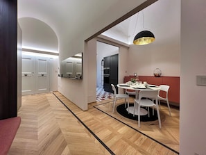 A modern kitchen with a dining area, featuring a herringbone wood floor, white cabinetry, and a black pendant light. - Residenza DuLà - Two Bedroom Apartment, Sleeps 6 (Arezzo)