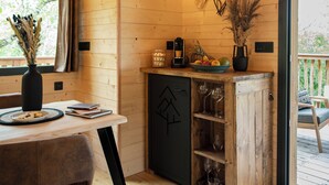 Ein gemütliches Blockhaus-Interieur mit einem Holzesstisch, einer Vase mit Trockenpflanzen und einer Kaffeemaschine.
