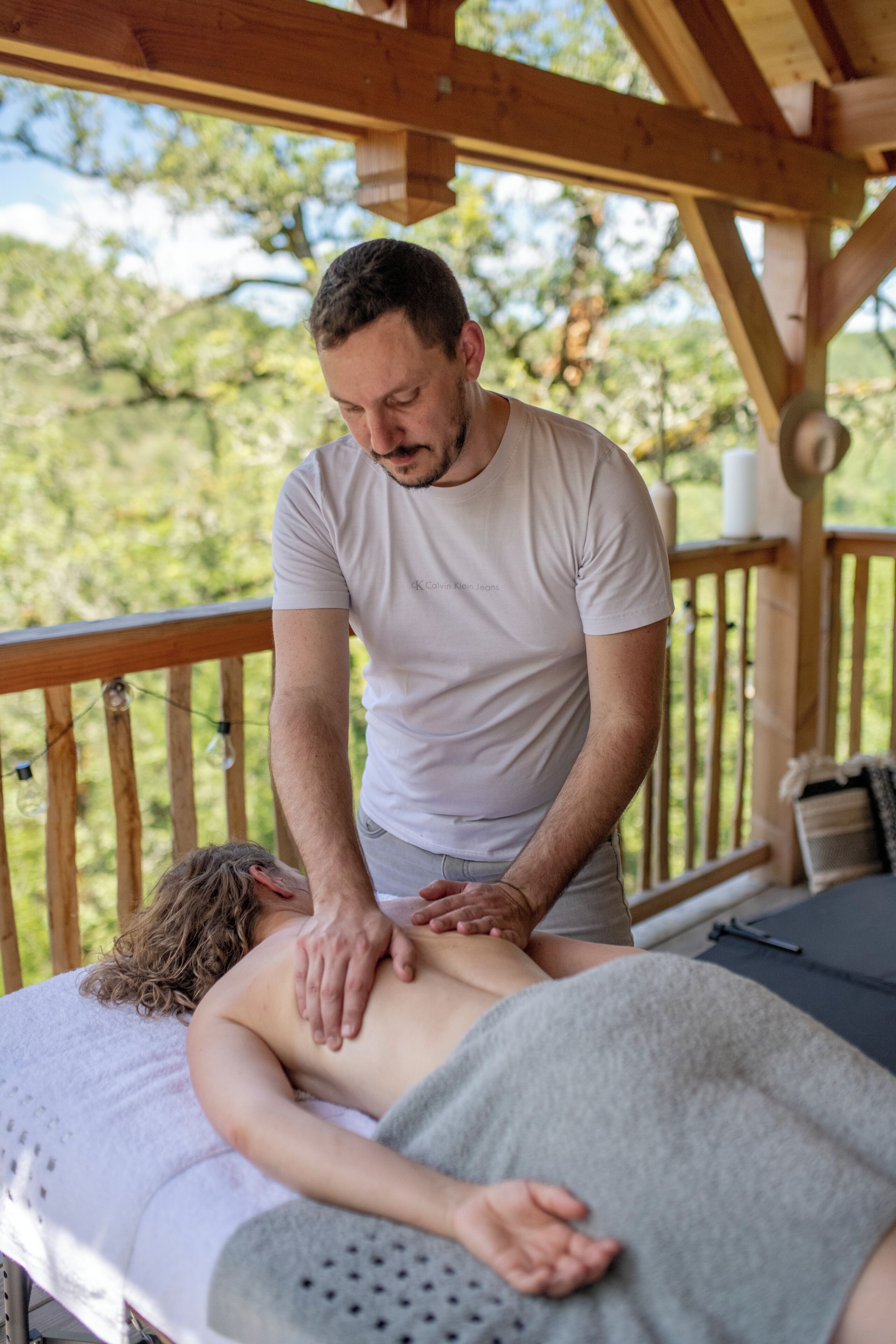 A wooden deck with a massage table and a person receiving a massage.