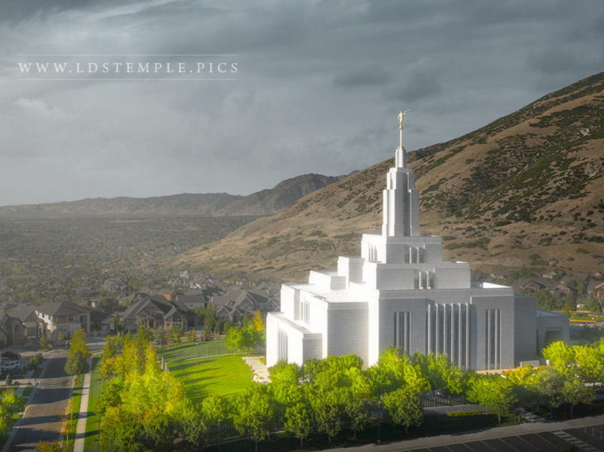 Una iglesia blanca con un campanario alto, rodeada por una zona residencial con casas y árboles.