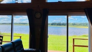 Quarto com amplas janelas e vista para um lago e barcos à vela.