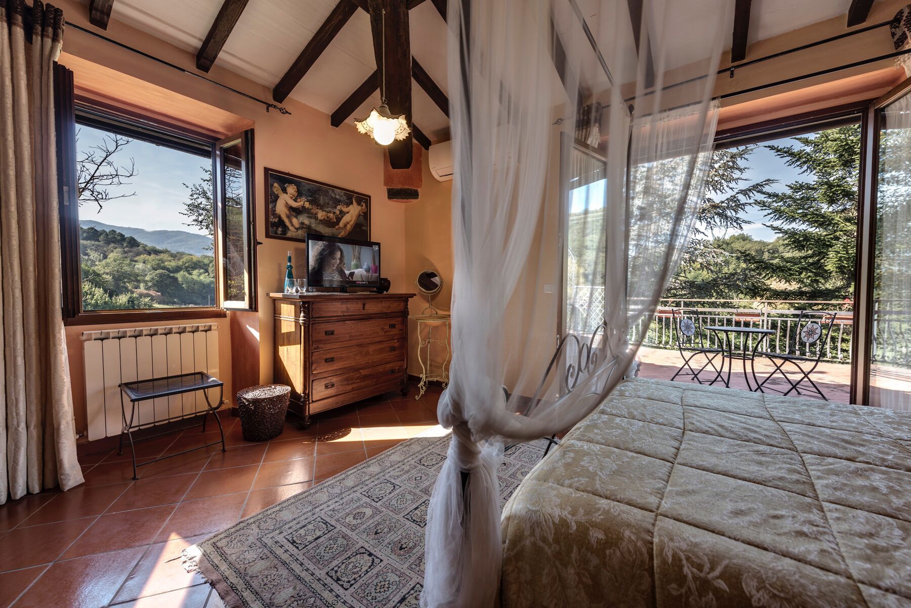 Une chambre à coucher avec un grand lit, une commode, un téléviseur et une vue sur l’extérieur.
