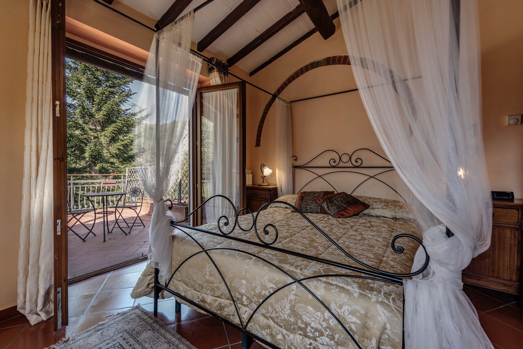 Une chambre à coucher avec un lit, une table de chevet, une lampe et une vue sur l’extérieur.