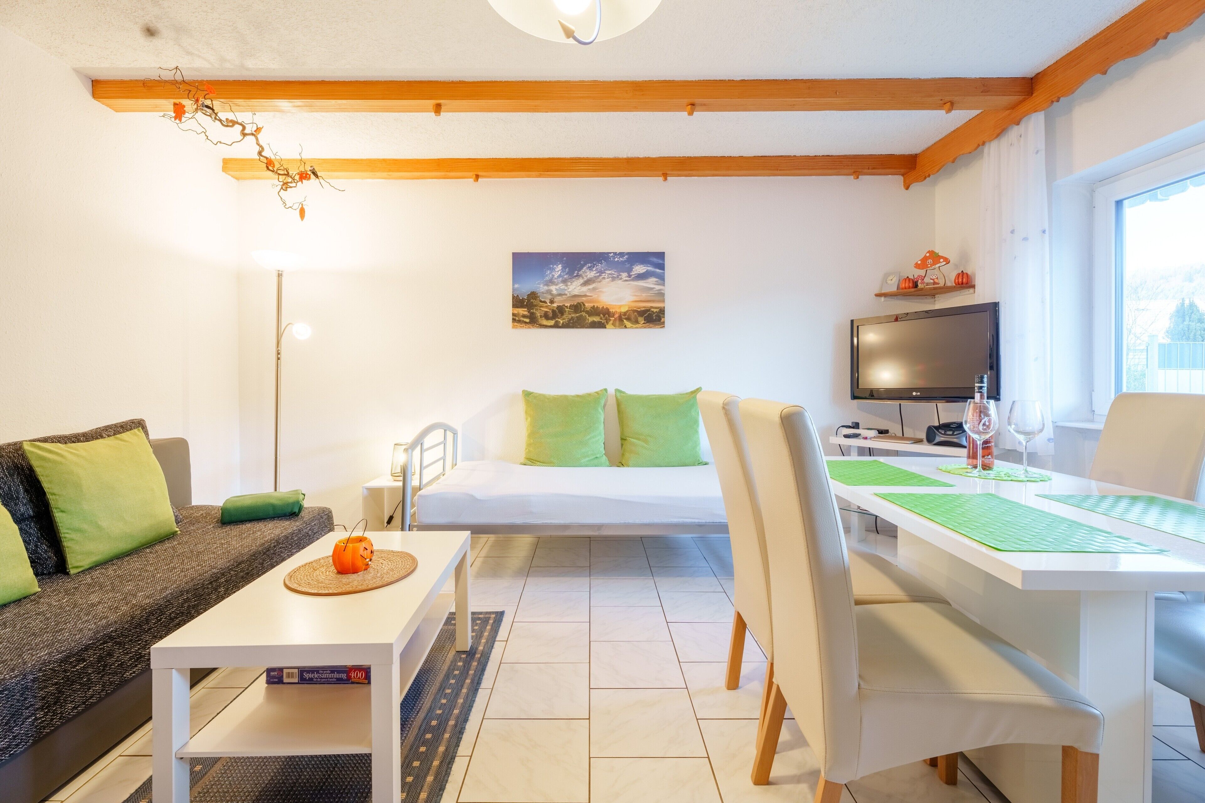 Een moderne woonkamer met een bank, een eettafel, een televisie en een schilderij aan de muur.