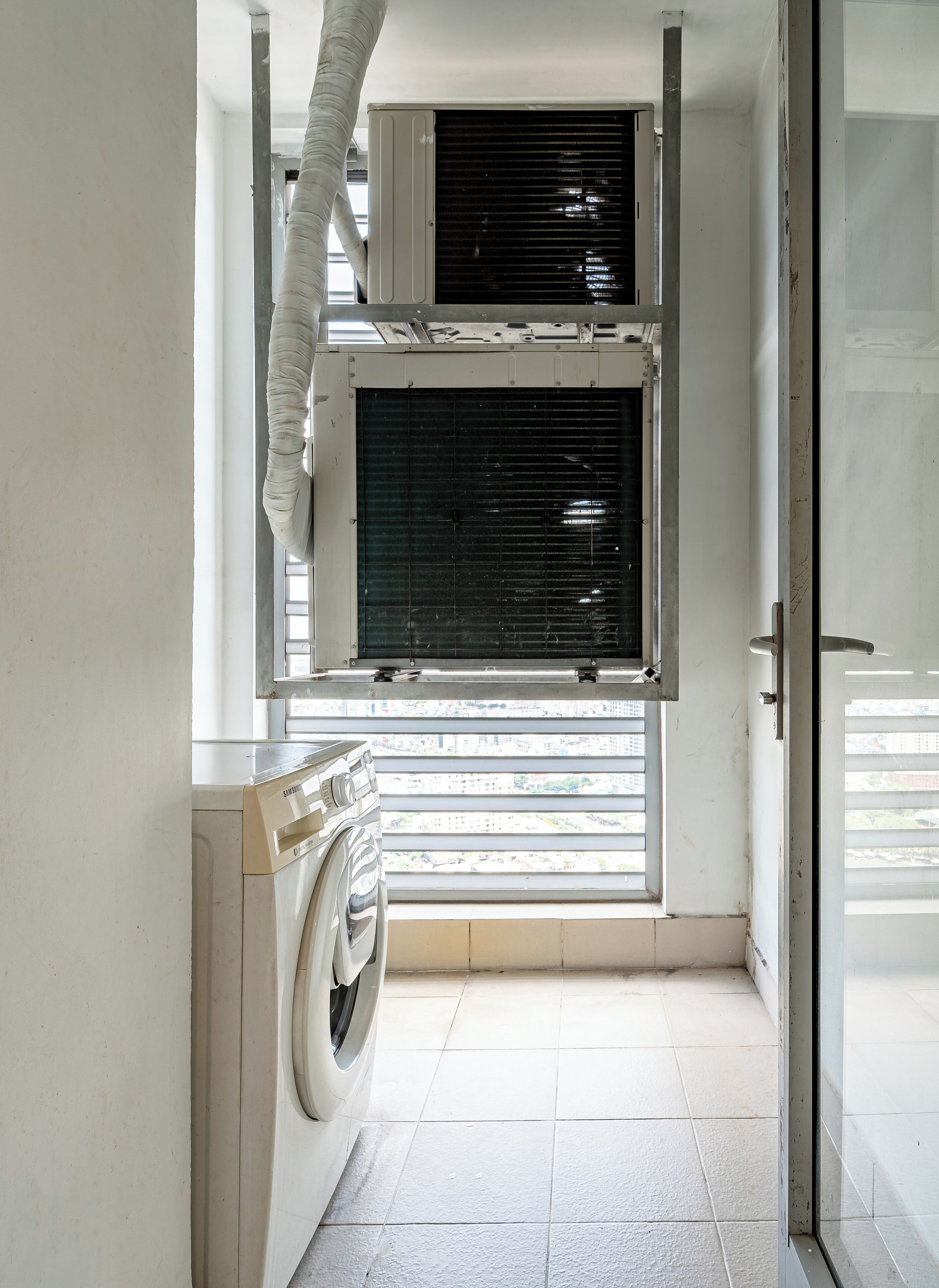 A laundry area with a washing machine and a window with blinds.