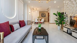 A modern living room with a sofa, a coffee table, and a dining area with chairs. - Horizon Panorama Apartment Vinhomes  (Ho Chi Minh City)