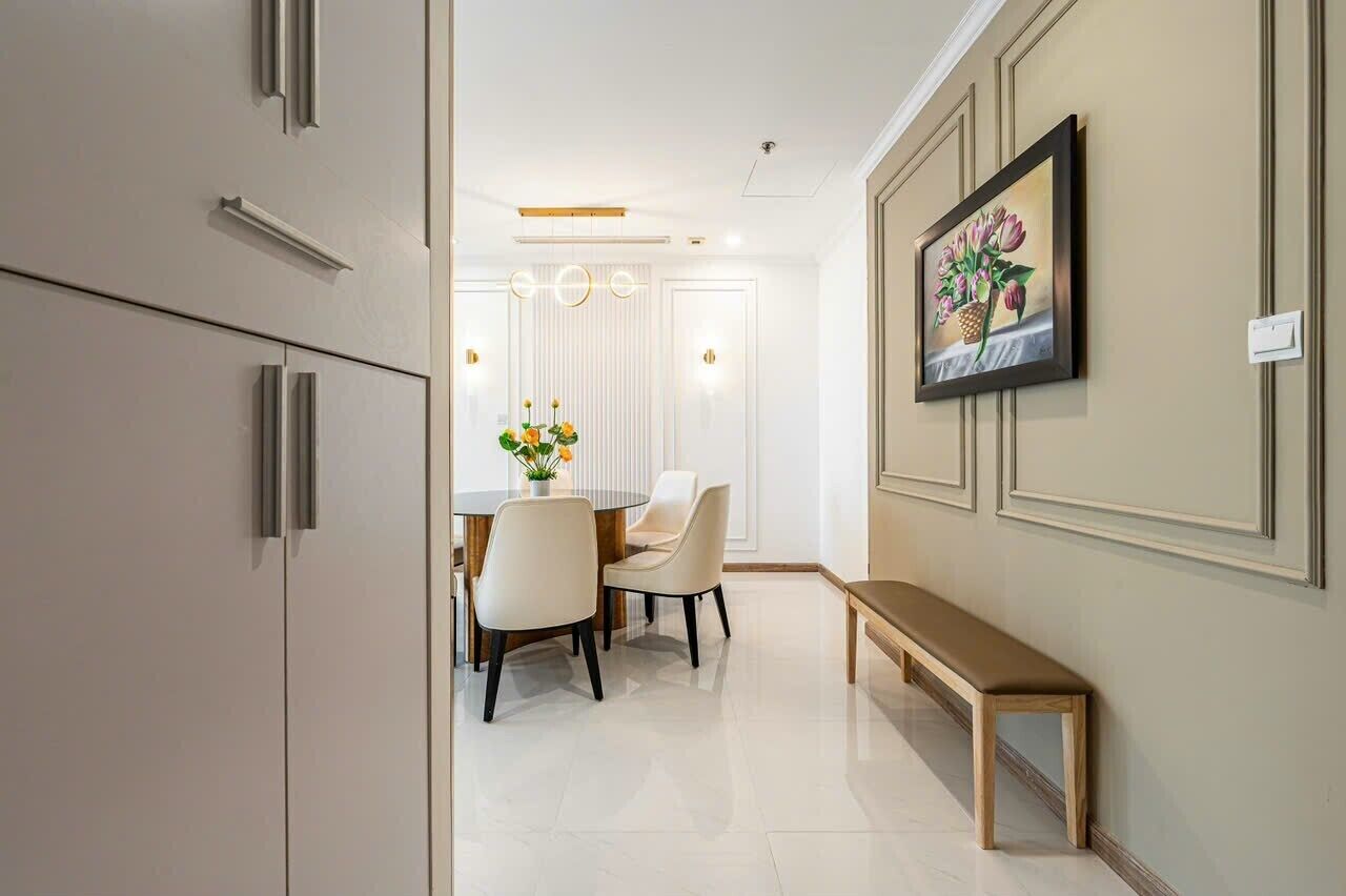 A modern interior with a dining area featuring a round table and chairs, a bench, and a wall-mounted painting.
