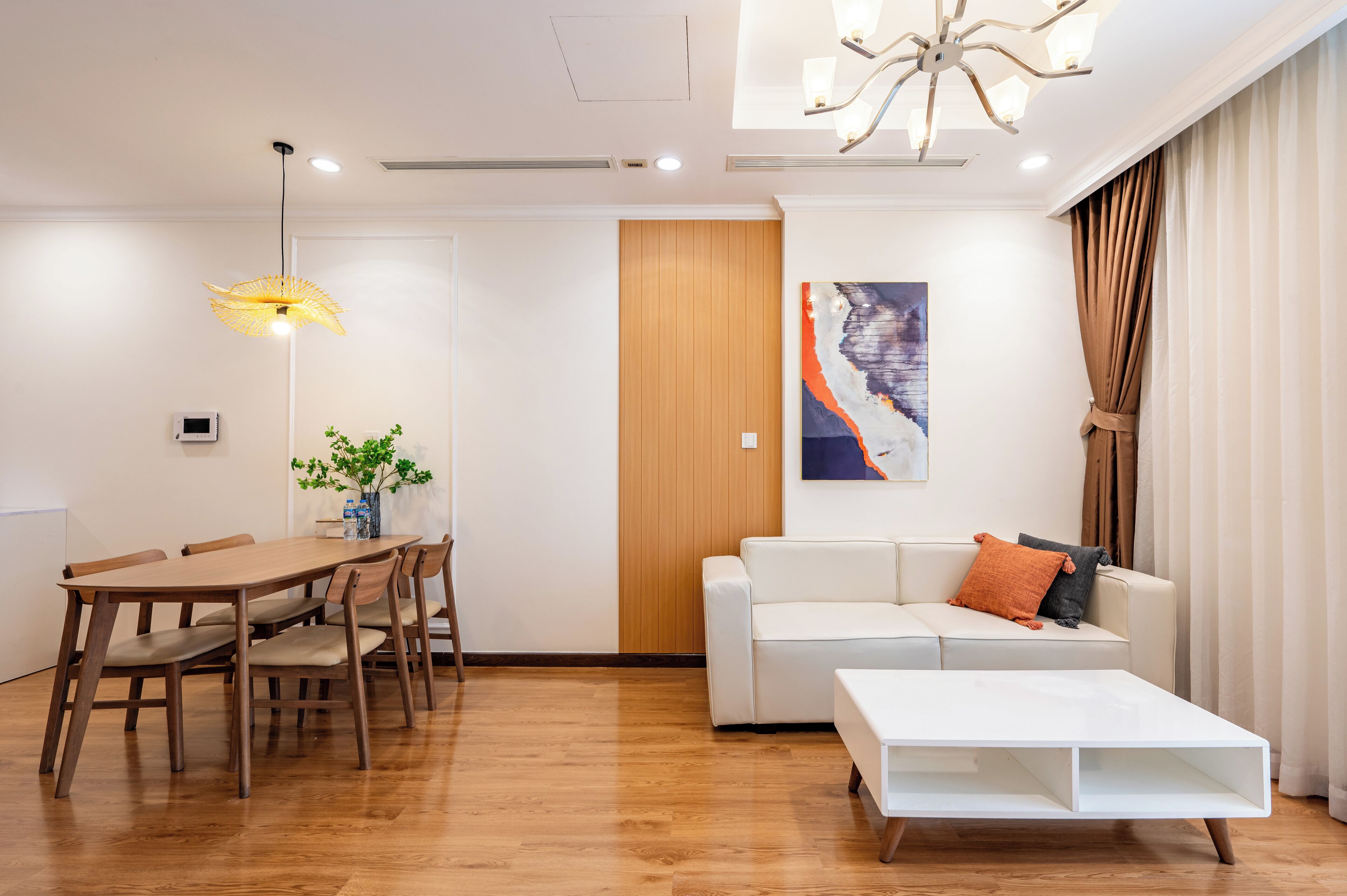 Una sala de estar moderna con una mesa de comedor de madera, un sofá blanco y una mesa de centro blanca.