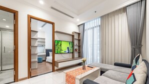 A modern living room with a flat-screen TV, a sofa, a coffee table, and a TV stand. - Horizon Panorama Apartment Vinhomes  (Ho Chi Minh City)