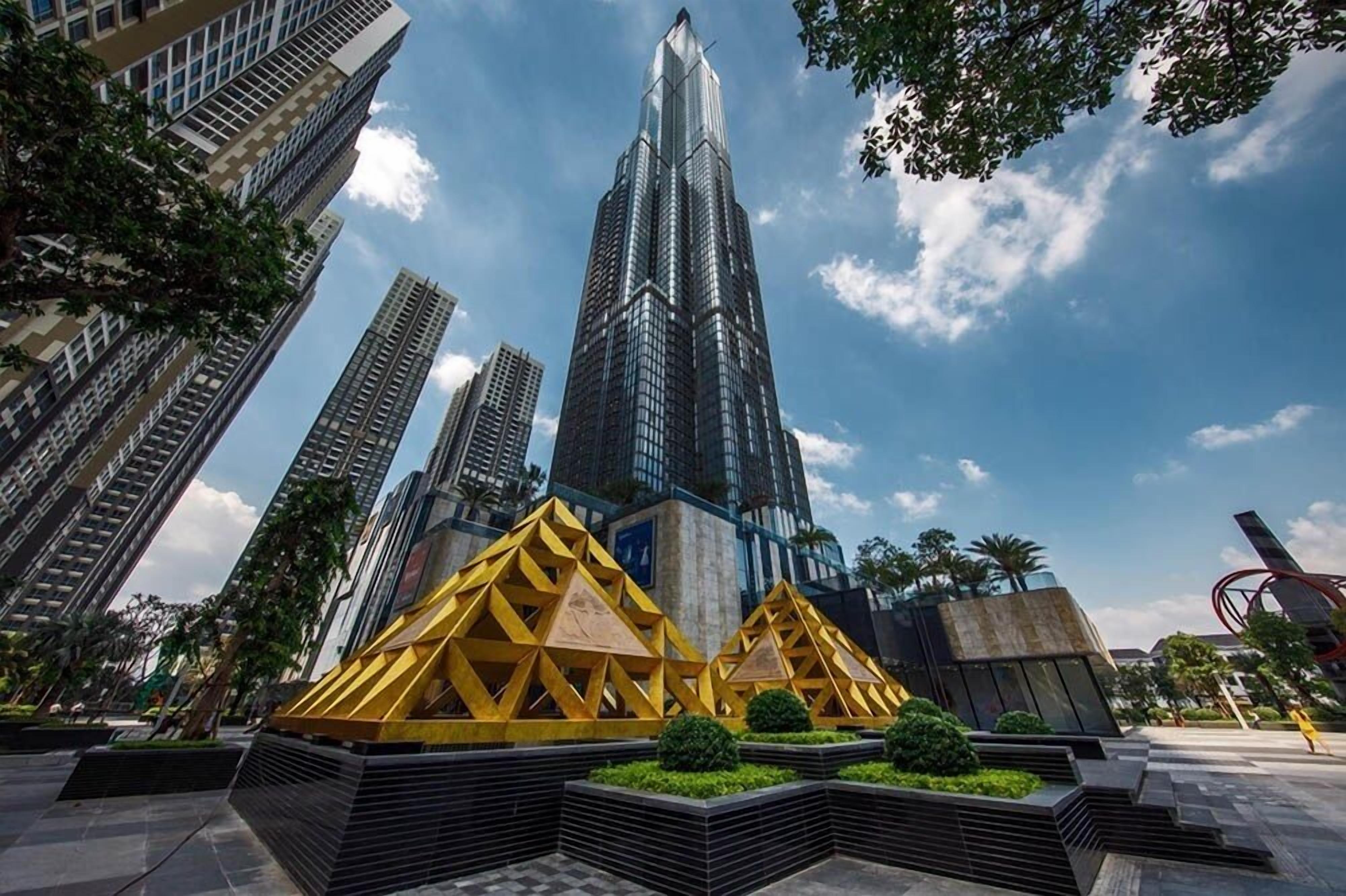 A modern skyscraper with a unique triangular structure in the foreground, surrounded by other high-rise buildings.