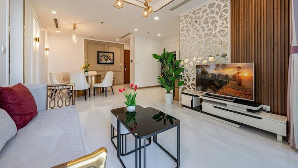 A modern living room with a sofa, coffee table, TV, and decorative plants.