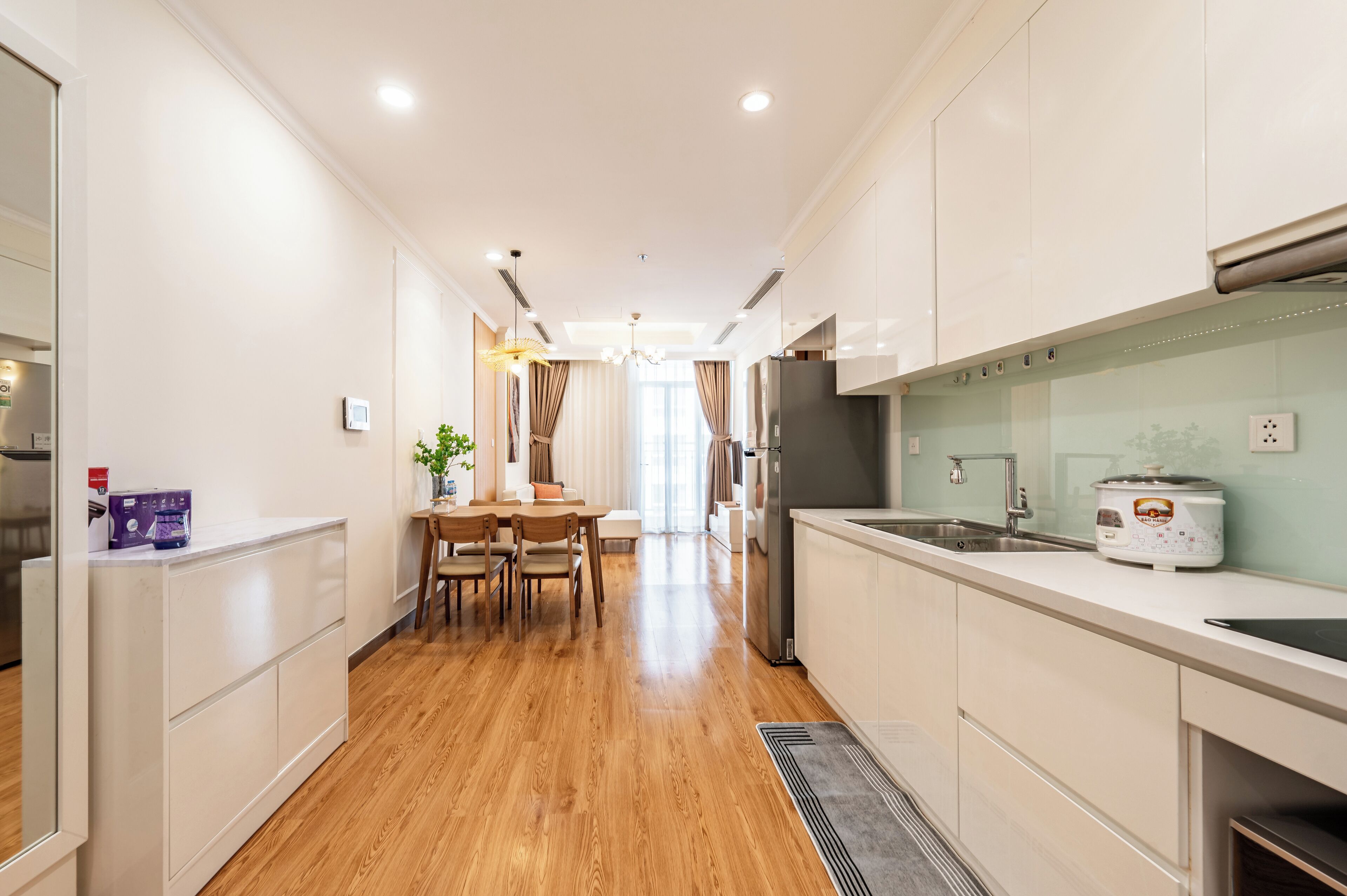 A modern kitchen with white cabinets, a stainless steel refrigerator, and a built-in oven.
