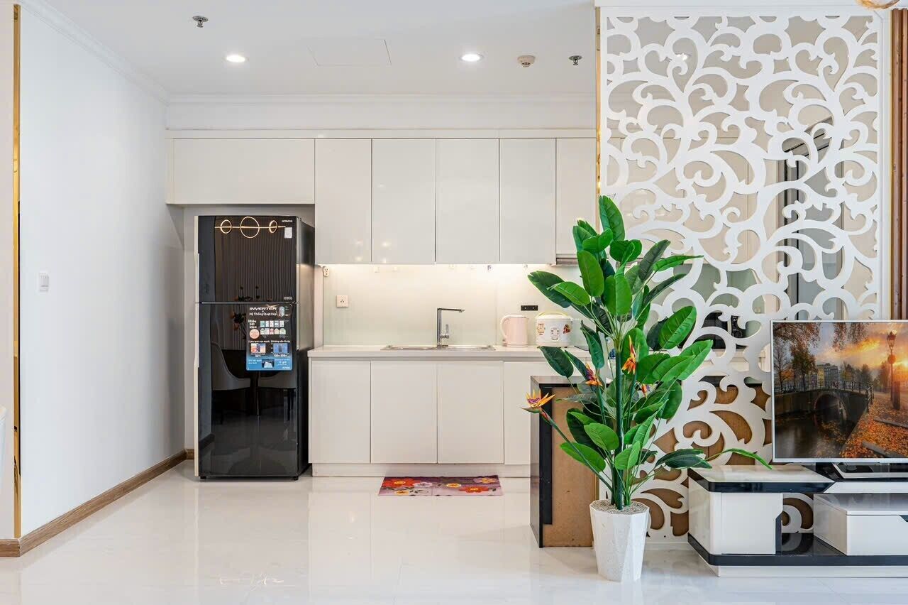 Une cuisine moderne avec des meubles blancs, un réfrigérateur encastré et un panneau décoratif mural.