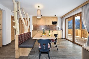 Une cuisine moderne avec des meubles en bois, une table à manger avec un banc, et une grande fenêtre donnant sur l’extérieur.