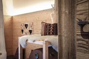 A wooden cabin interior with a bed, a heart-shaped decoration, and a rustic door. - Apartment 'Ban Rutzner Plose' with Mountain View, Shared Terrace and Wi-Fi (SantʼAndrea in Monte)