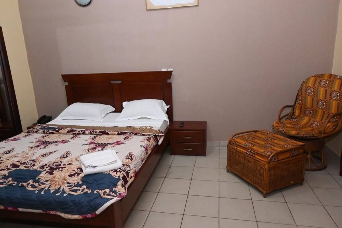 Une chambre à coucher comprenant un lit, une table de chevet, une chaise et une commode en osier.