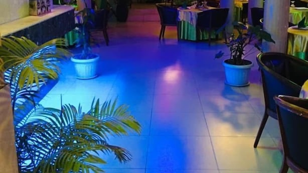 Een restaurant met een open centrale ruimte, potplanten en een betegelde vloer.