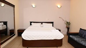 Een slaapkamer met een groot bed, een bank, een spiegel en wandlampen.