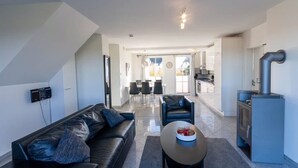 En moderne stue med sofa, sofabord og et køkkenområde med komfur.