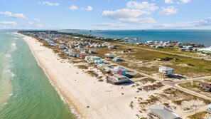 Ein Luftbild einer Küstenregion mit Strandhäusern, einer Marina und einer Straße entlang des Ufers.