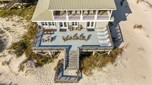 Ein Hotel direkt am Strand mit einer Terrassenfläche, die Sitzmöglichkeiten im Freien und eine Treppe zum Gebäude bietet.