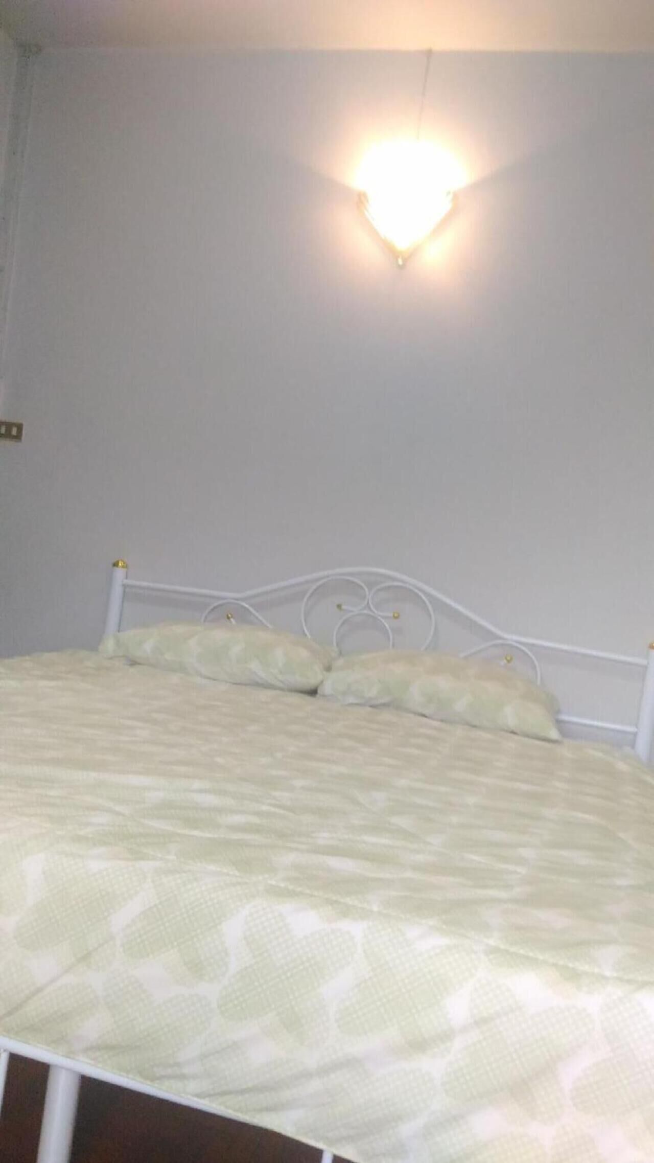 Ein Bett mit weißem Metallgestell und einem gemusterten Bettbezug.