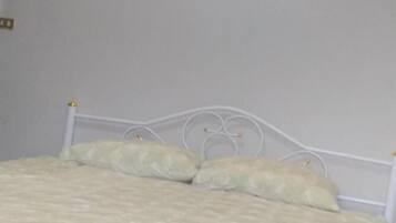 Ein Bett mit weißem Metallgestell und einem gemusterten Bettbezug.
