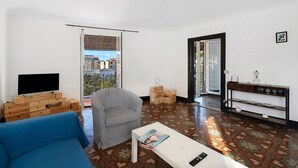 A living room with a blue sofa, a striped armchair, a coffee table, a TV, and a patterned floor. - Apartment 'Casa Terrazza Marino' with Private Terrace and Wi-Fi (Levanto)