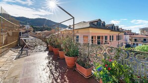 A balcony with potted plants, a metal railing, and a view of buildings and hills in the background. - Apartment 'Casa Terrazza Marino' with Private Terrace and Wi-Fi (Levanto)