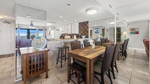 Una cocina moderna con armarios blancos, una mesa de comedor de madera y una barra.