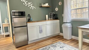A kitchen with a stainless steel refrigerator, wooden countertop, and a window with a view of trees. - Hidden Oaks | The Cottage | Unit 1 (Birch Run Township)